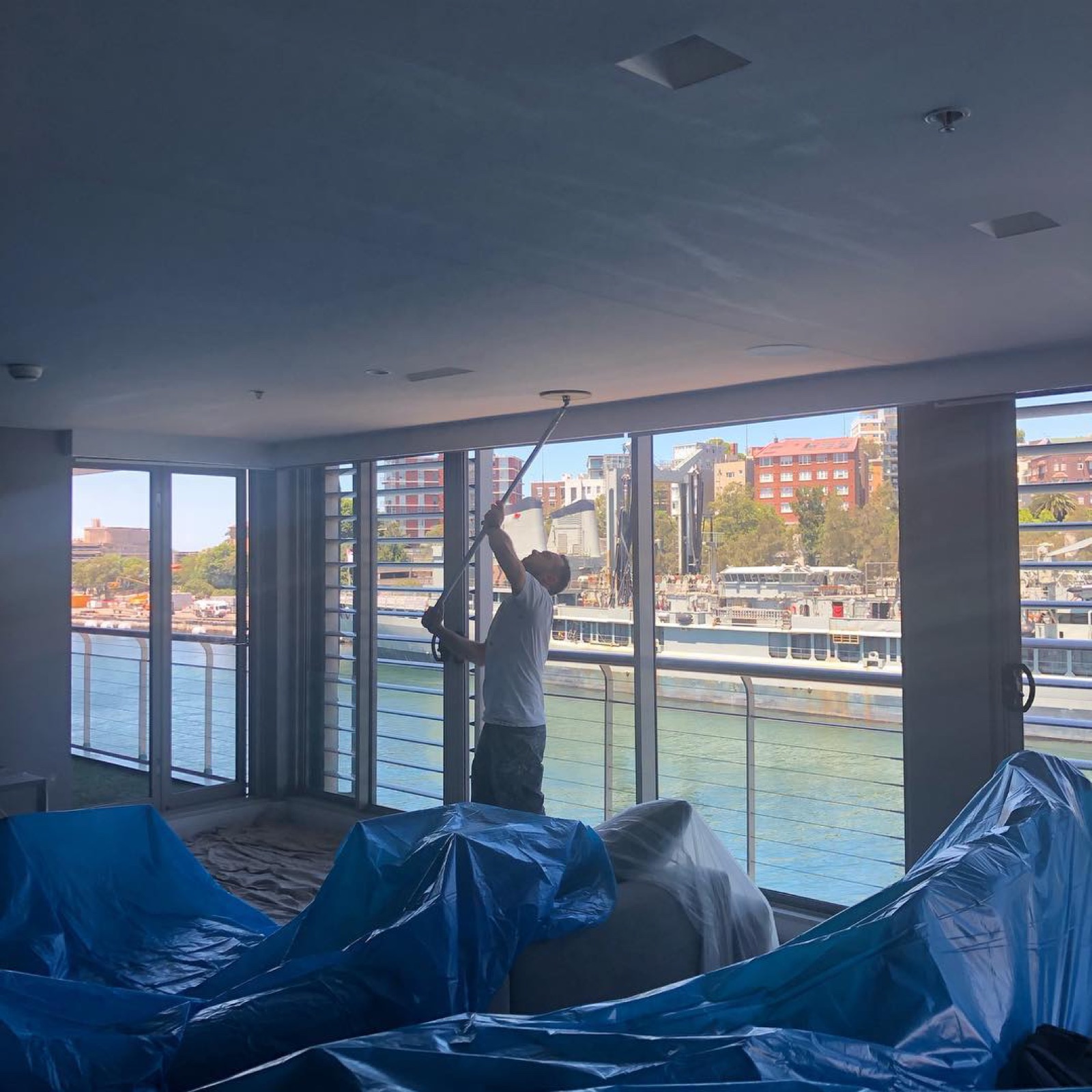 Painter rolling a ceiling in a waterfront apartment