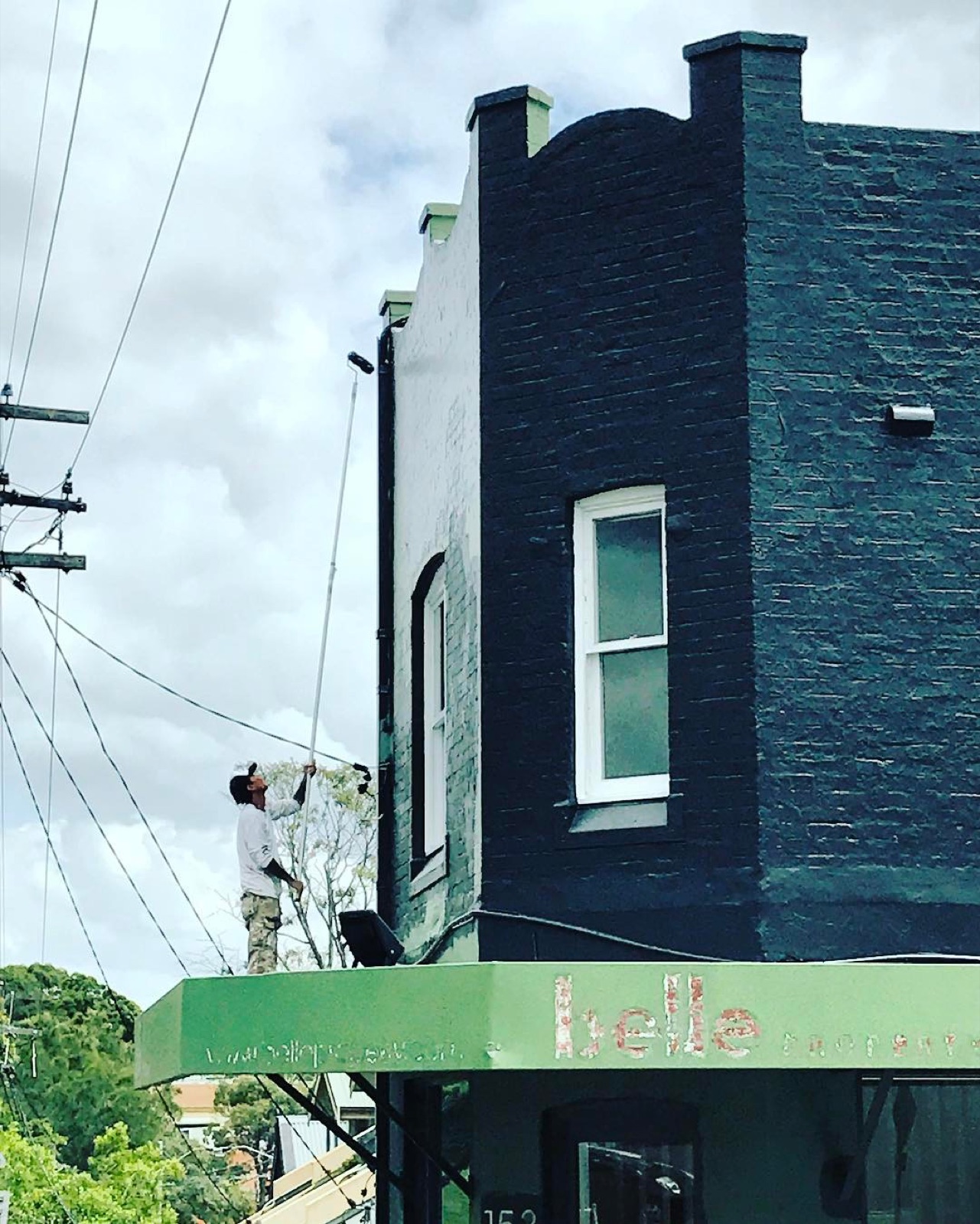 Painter on an awning painting a commercial corner building