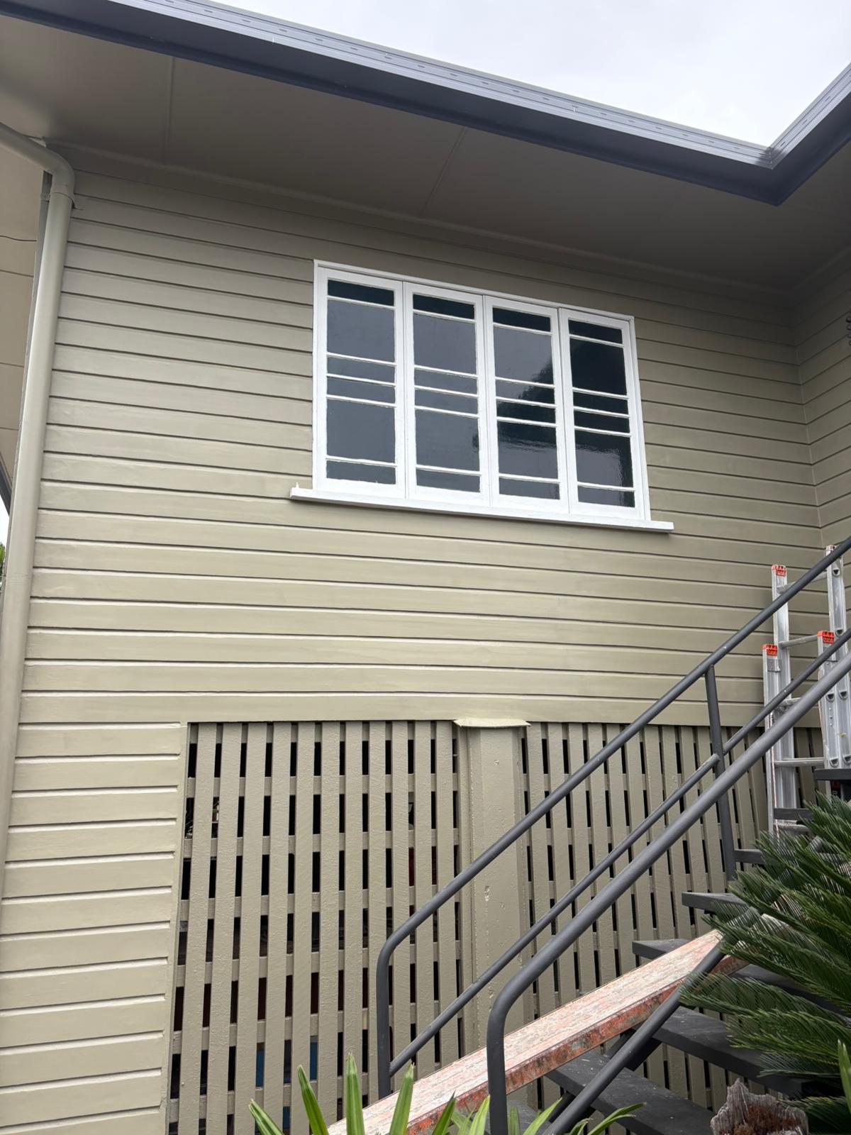 Freshly painted olive-green weatherboard on a high-set Queenslander