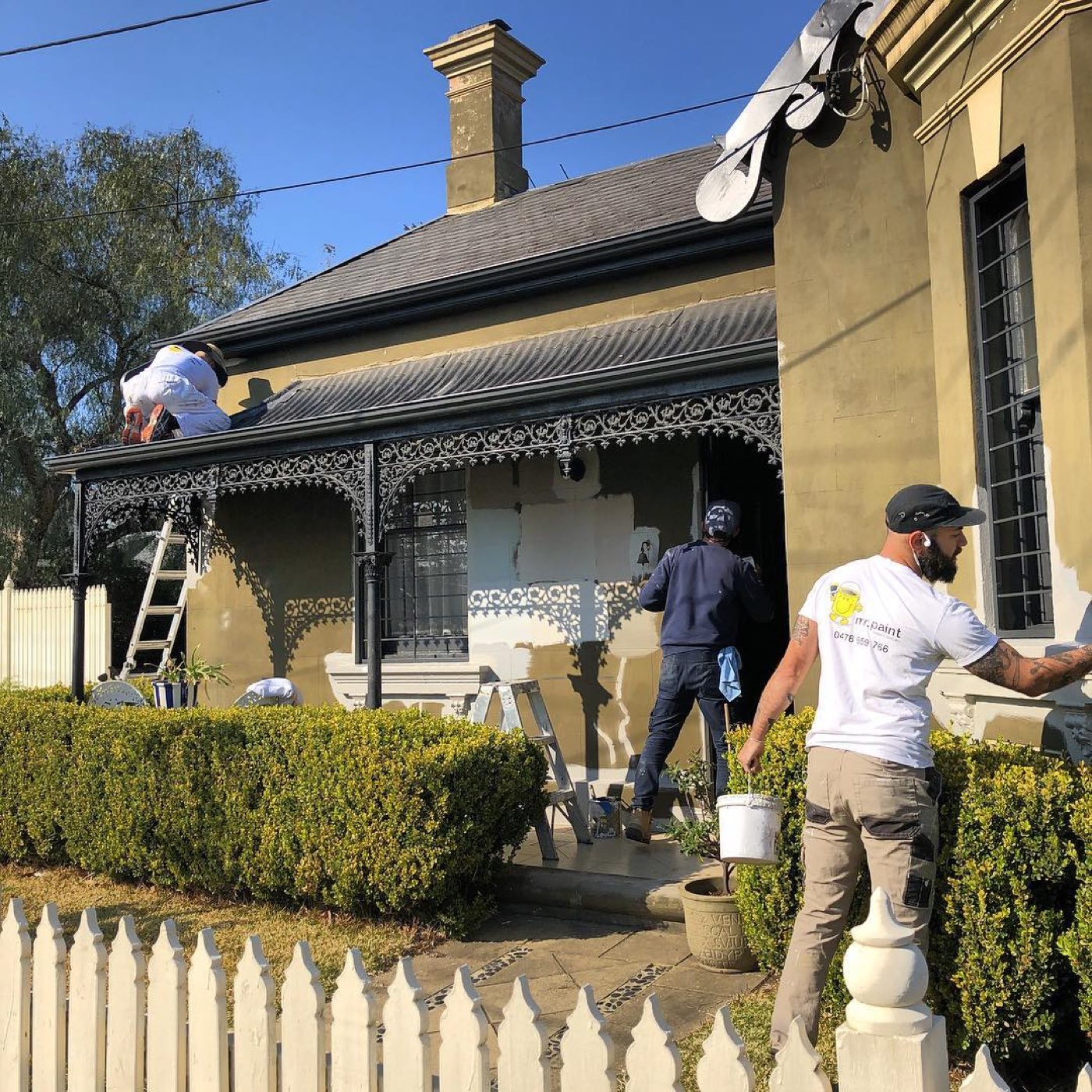 Crew painting a heritage cottage with lacework verandah